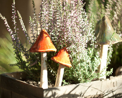 Dwa ceramiczne grzybki ogrodowe w drewnianej donicy