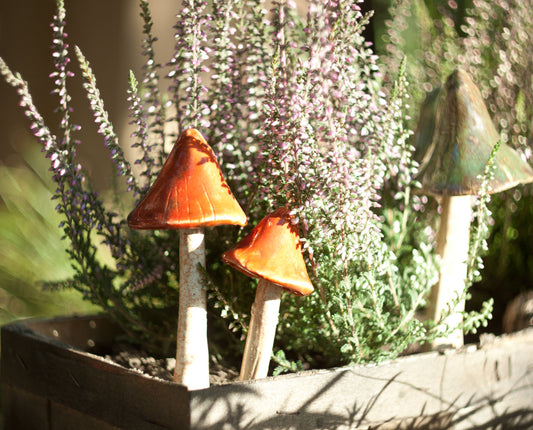 Dwa ceramiczne grzybki ogrodowe w drewnianej donicy